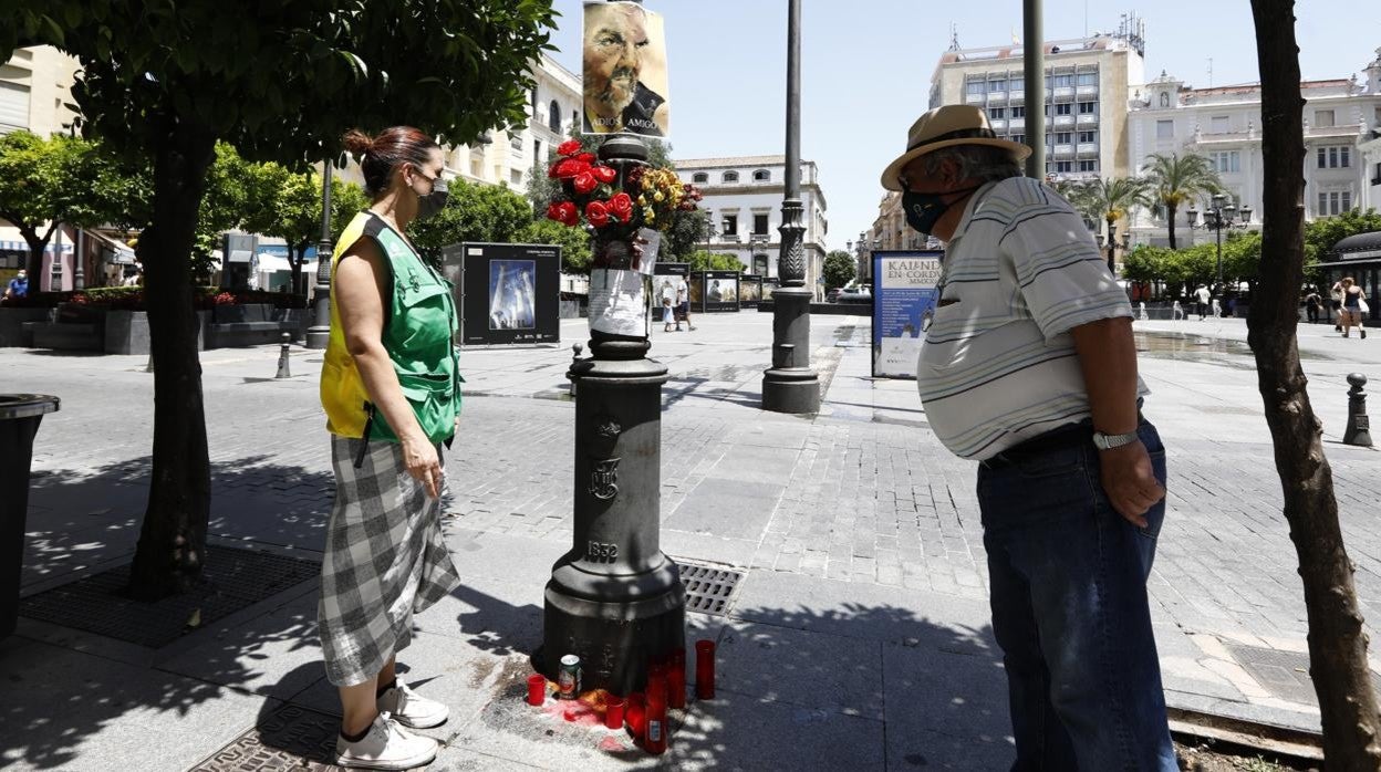 Dos conocidos del hombre fallecido, junto a las flores y las velas que lo recuerdan