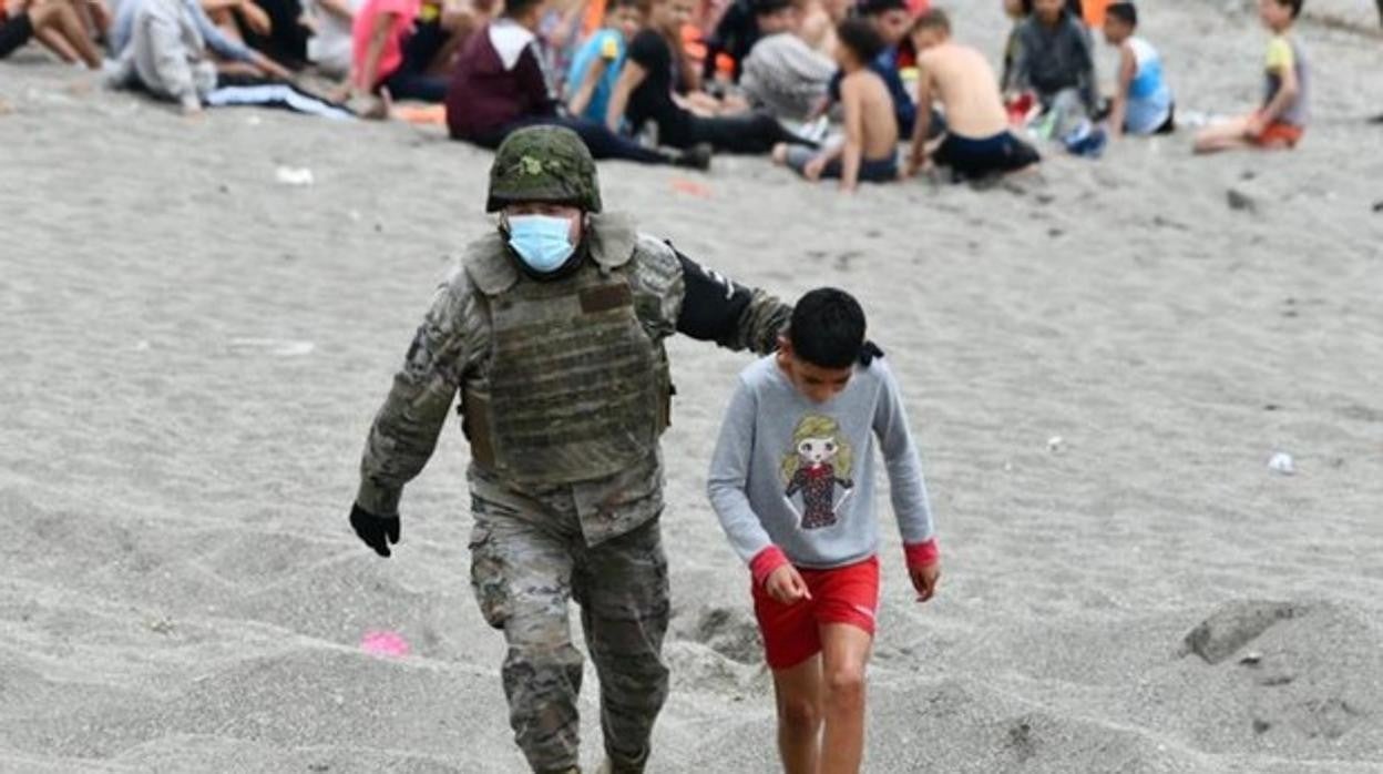 Uno de los niños llegados a Ceuta escoltado por un militar