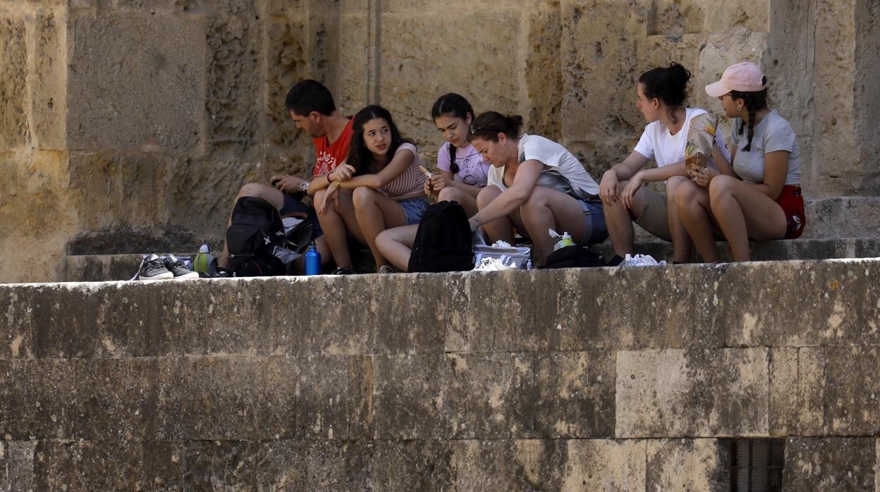 Un grupo de jóvenes descansa en las gradas de la Mezquita-Catedral de Córdoba