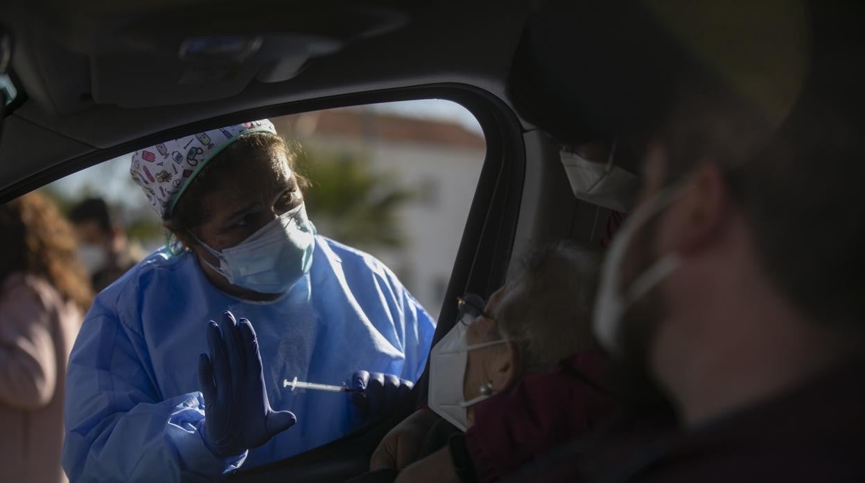 Una mujer mayor de 90 años recibe desde el coche la vacuna contra el Covid-19 en Lora del Río