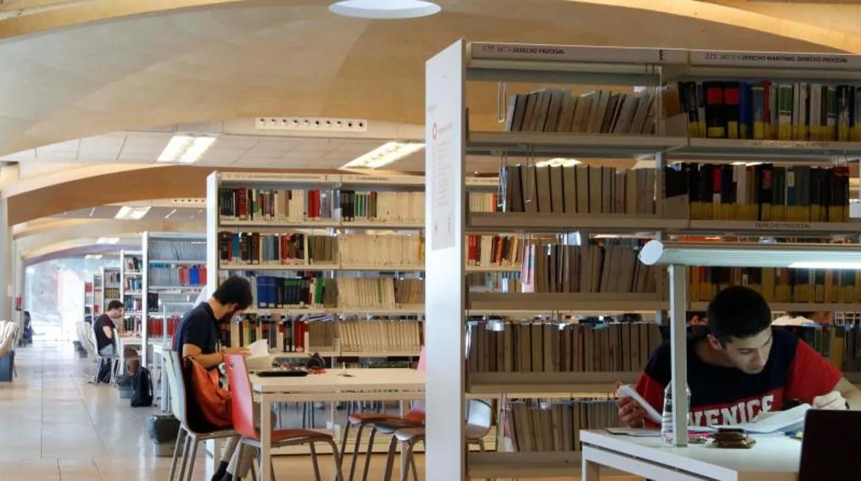 Estudiantes universitarios en una biblioteca manteniendo las distancias y las medidas Covid