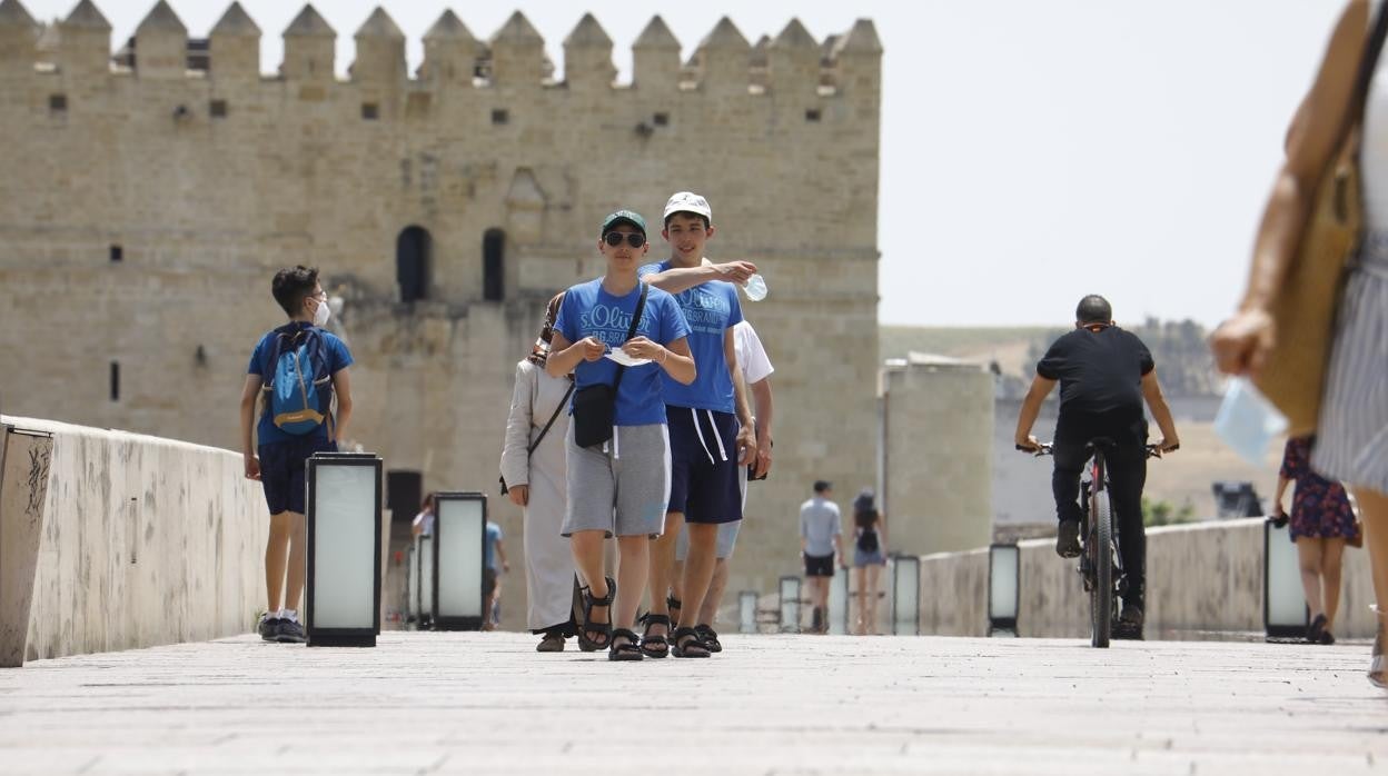 Varios jóvenes pasan en chanclas por el Puente Romano de Córdoba