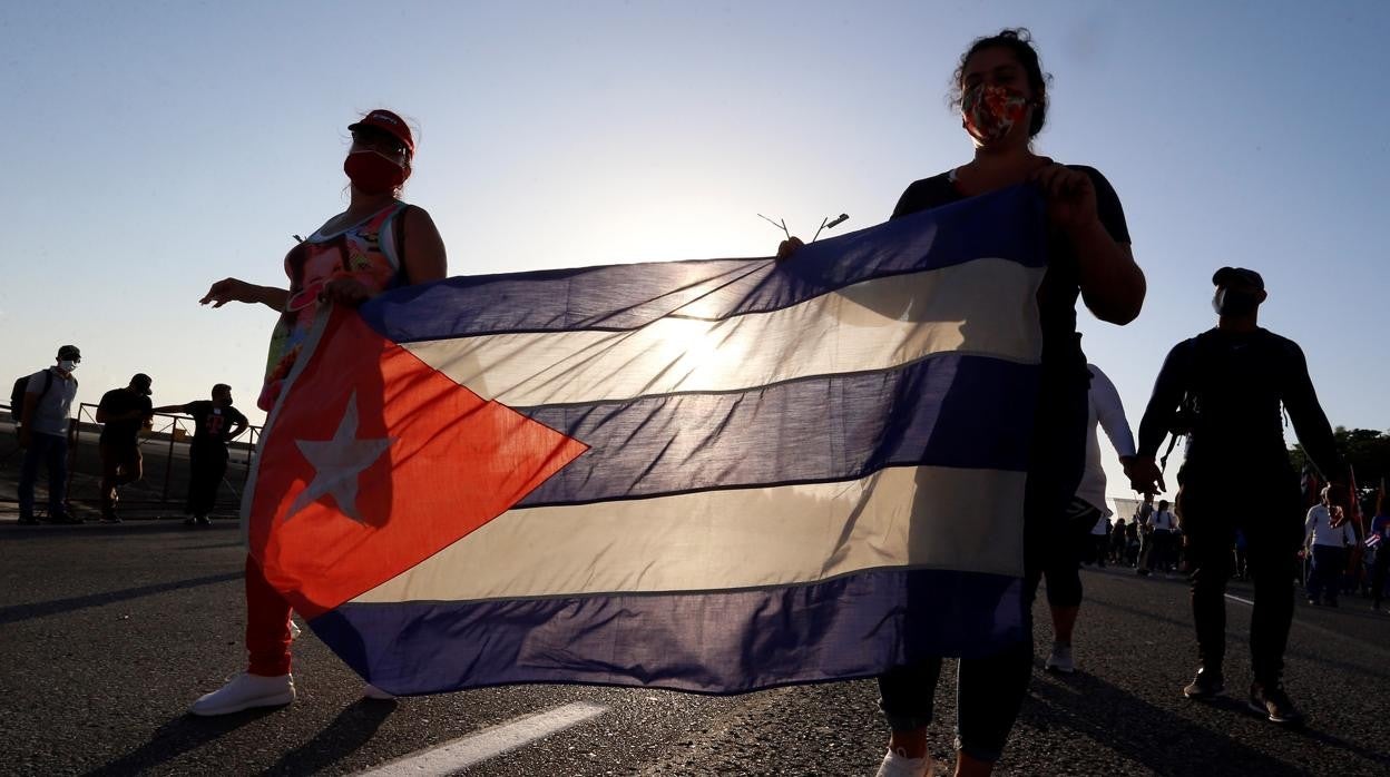 Imagen a contraluz de dos mujeres con la bandera de Cuba en La Habana