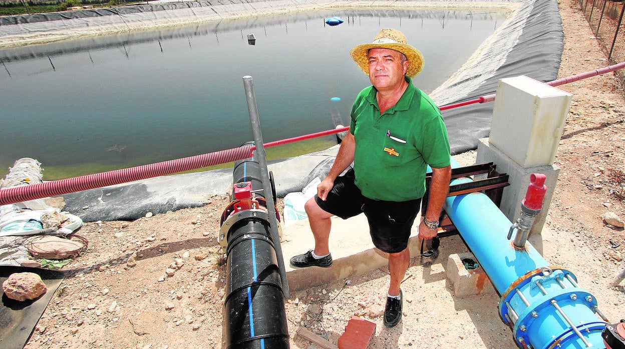 Un regante, junto a la instalación de una bomba de agua cerca de una balsa para los cultivos