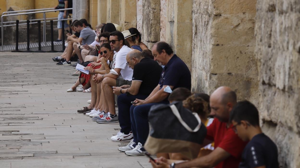 Un grupo de turistas descansa sentados a la sombra en el Patio de los Naranjos durante la jornada de ayer