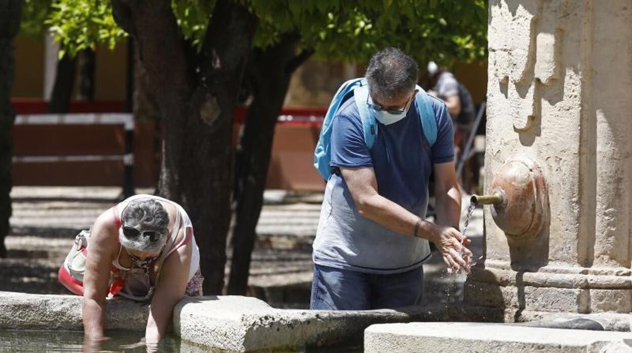 Dos turistas se refrescan en una fuente en Córdoba