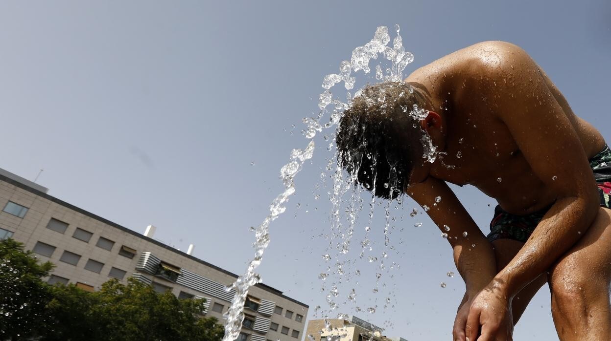 Un joven se refresca en una fuente pública de Córdoba