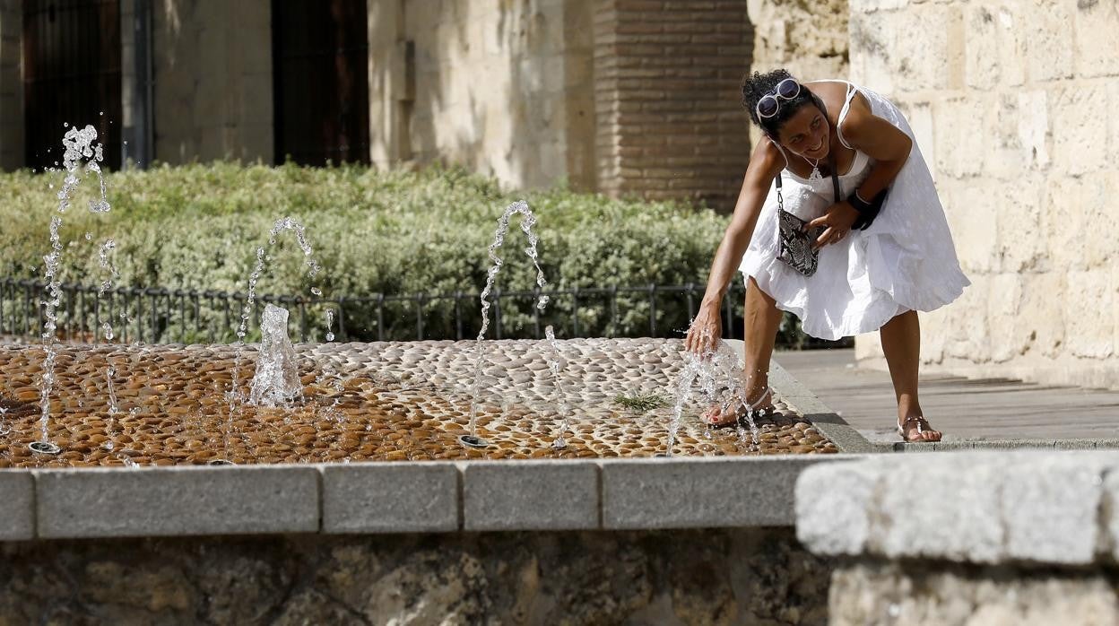 Una mujer se refresca en una fuente pública en Córdoba