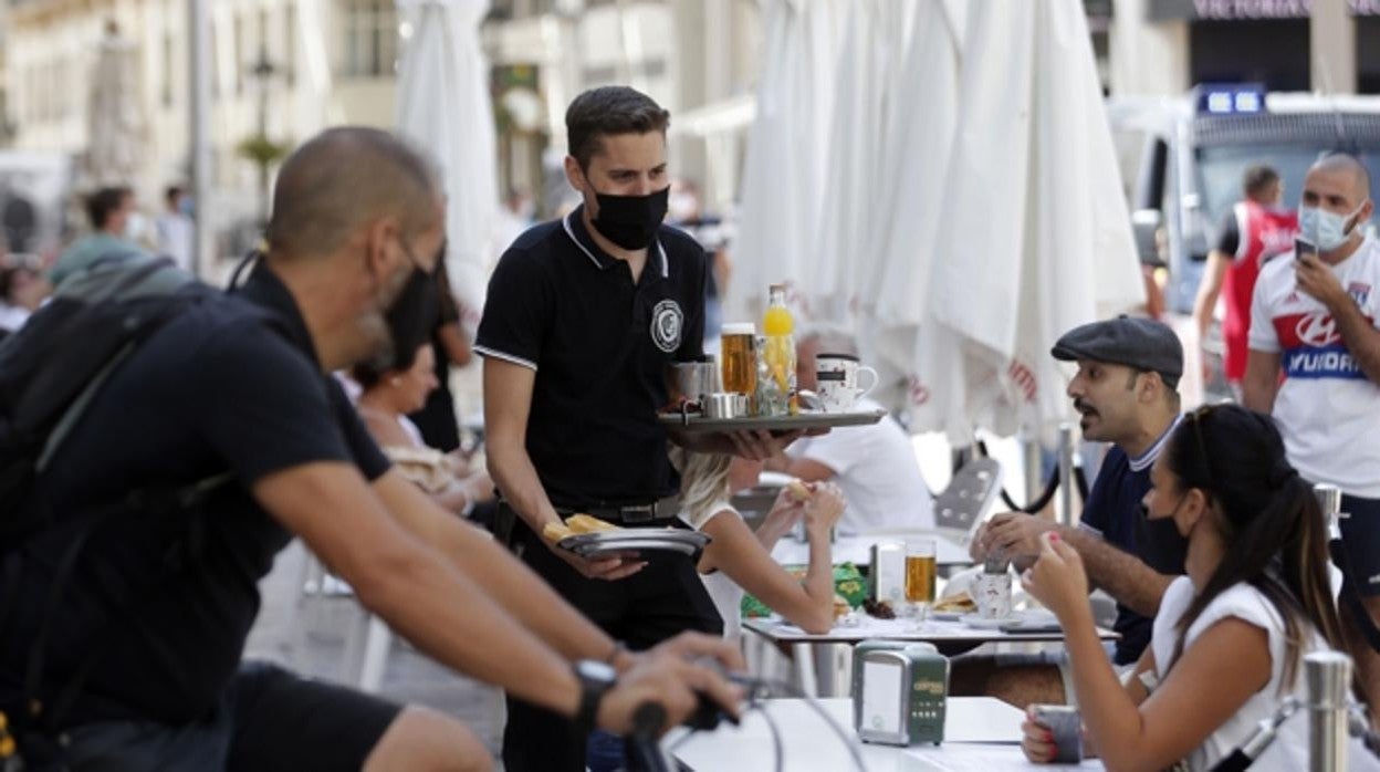 Un camarero sirve a una mesa en un establecimiento del centro de Málaga