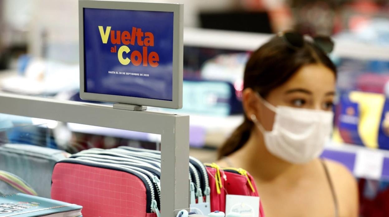 Una joven pasa delante de material escolar, con el cartel anunciador de la 'Vuelta al cole'