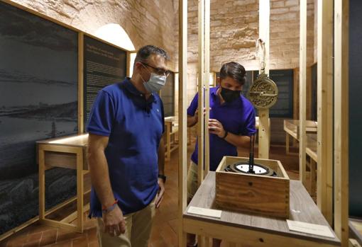 Dos hombres observan un compás moderno y una réplica de un astrolabio del siglo XVI; el instrumento permitía calcular la hora de noche, además de la posición y latitud de los astros