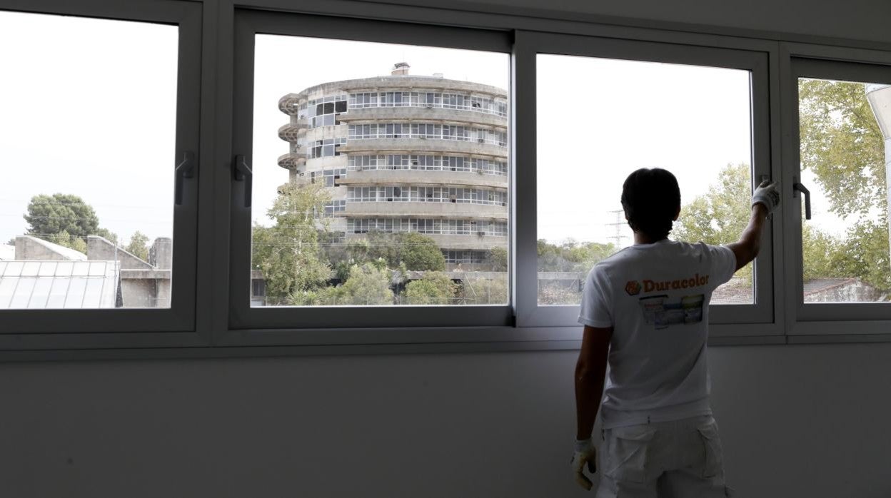 Un trabajador limpia una ventana del aulario con la torre de Agrónomos al fondo