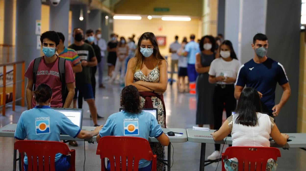 Jóvenes ante varios sanitarios en la cita para lavacunación en el Palacio de Deportes de Vista Alegre