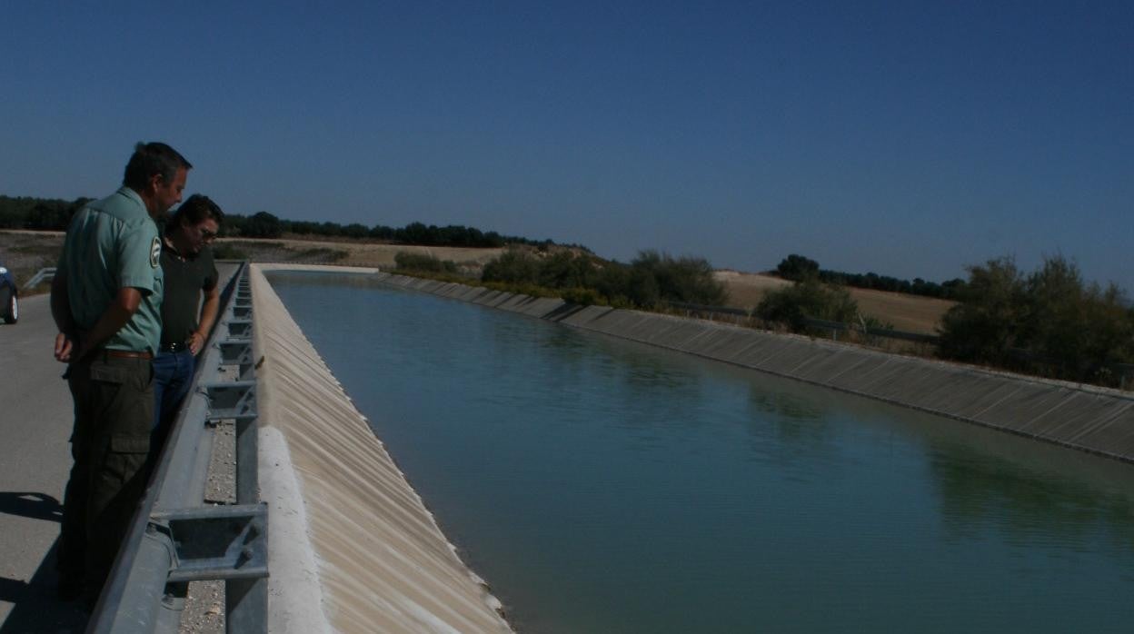 Dos personas miran un canal cerca de Aguilar de la Frontera