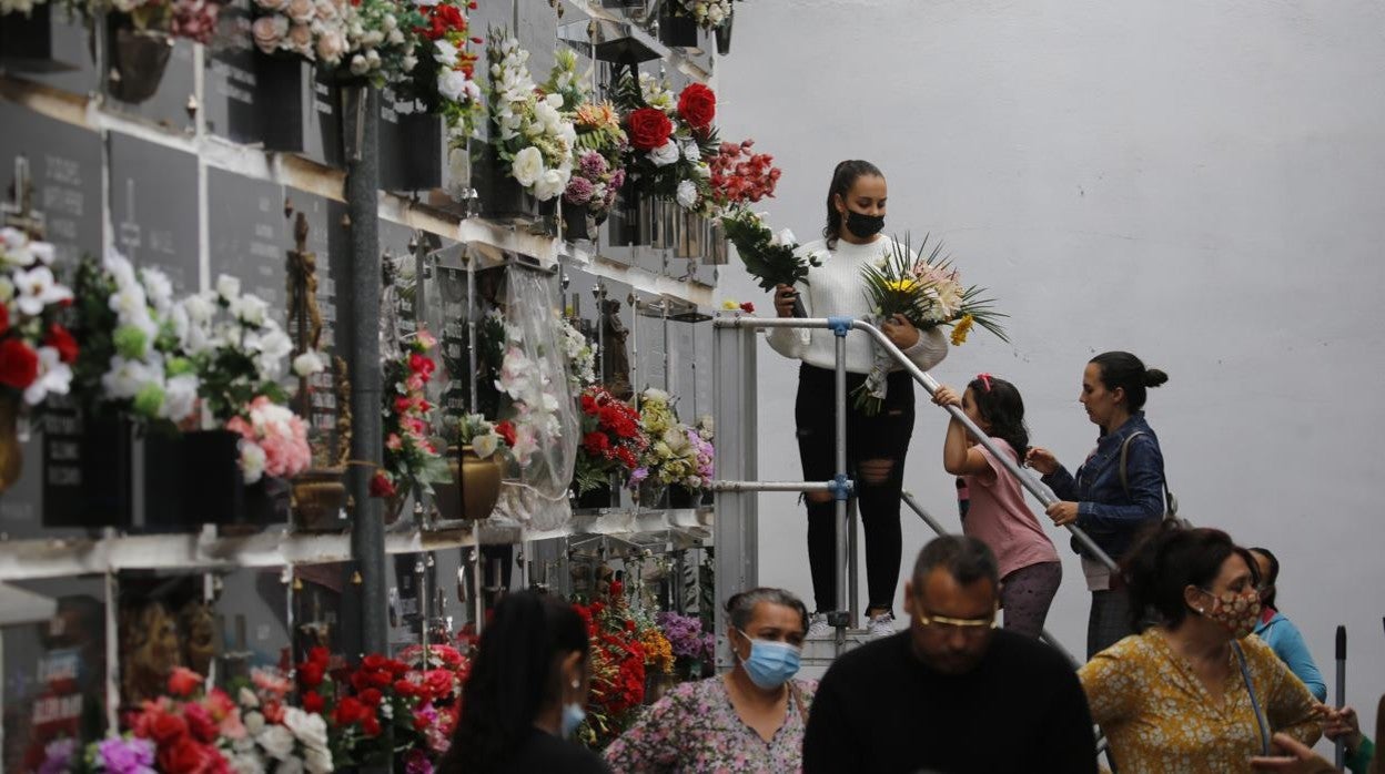 Una familia, colocando flores en un nicho en el cementerio de San Rafael el día de Todos los Santos