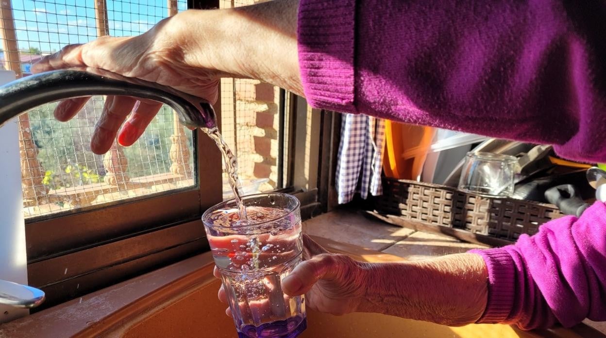 Una mujer llena un vaso de agua en un domicilio de Puente Genil