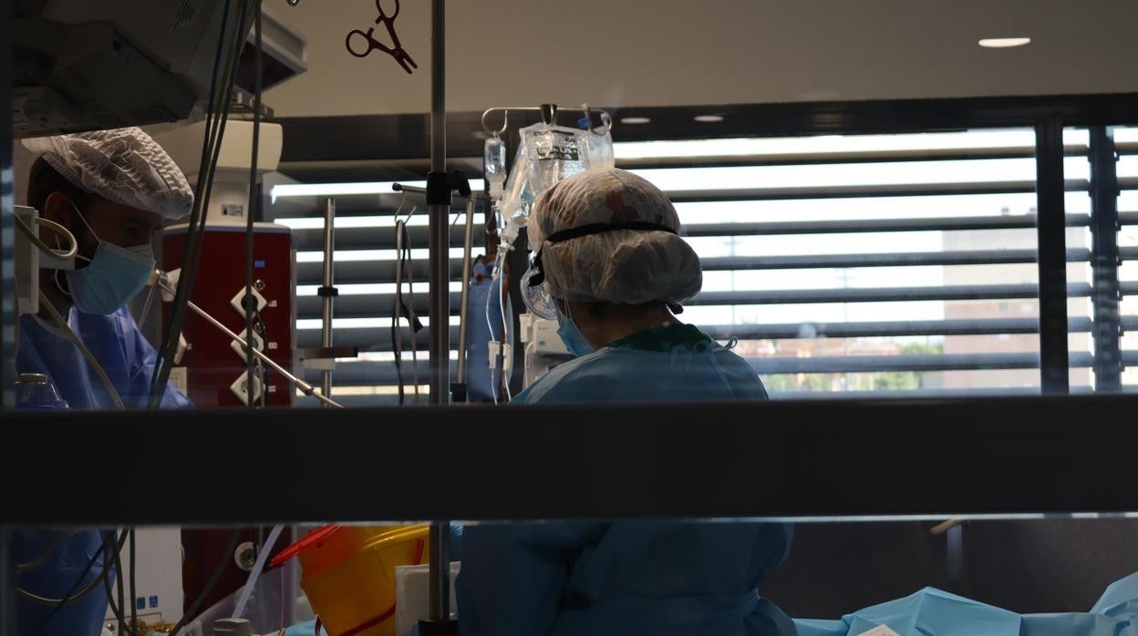 dos sanitarios atienden a un paciente en la UCI del Hospital Reina Sofía de Córdoba