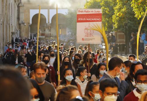 Jóvenes portando palmas en el nutrido cortejo, con el paso de los mártires al fondo