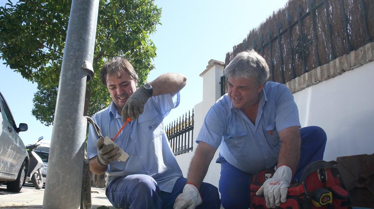 Dos operarios municipales arreglan una farola