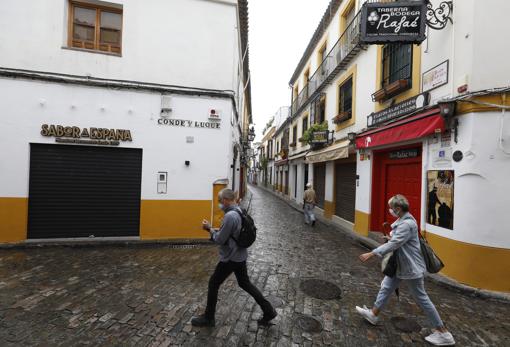 Turistas pasan ante negocios cerrados en mayo de 2020, en el inicio de la desescalada