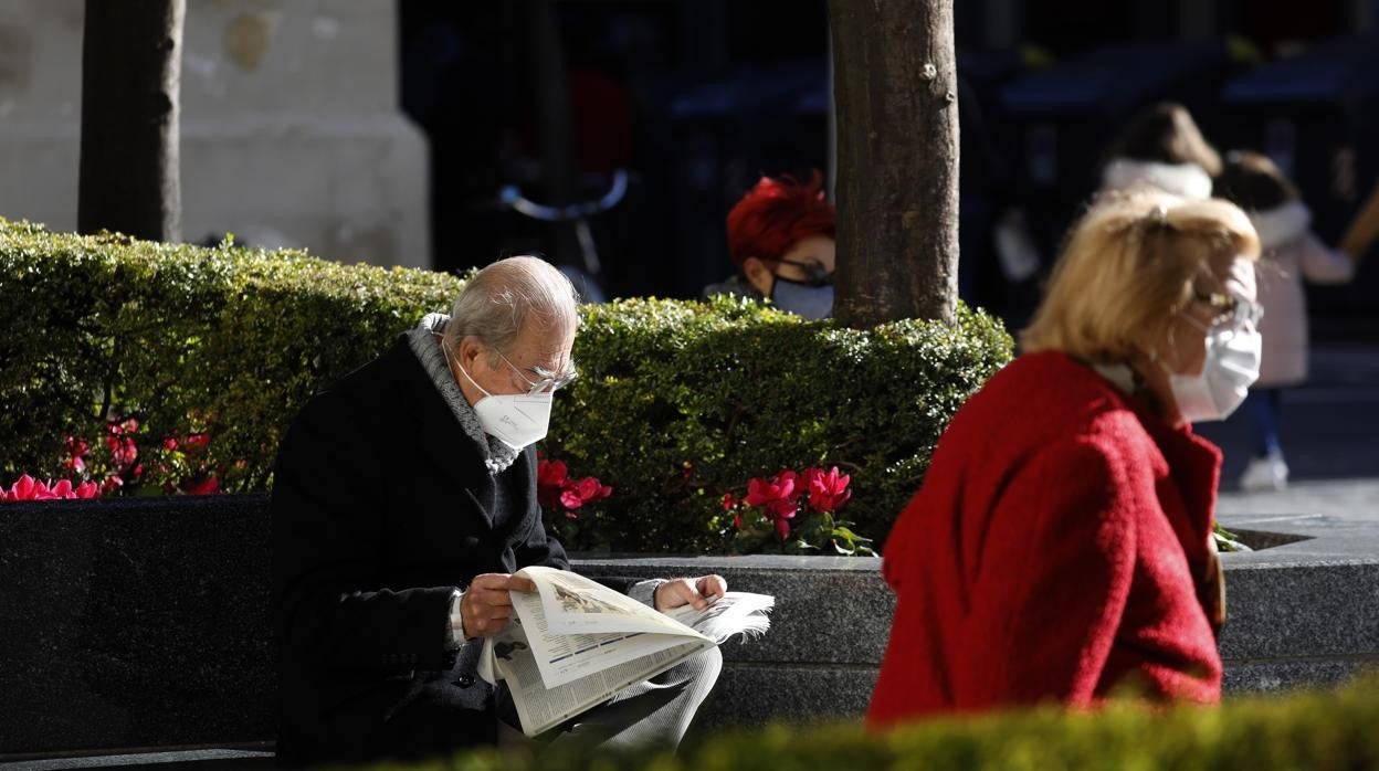 Un hombre lee el periódico en un banco de Las Tendillas