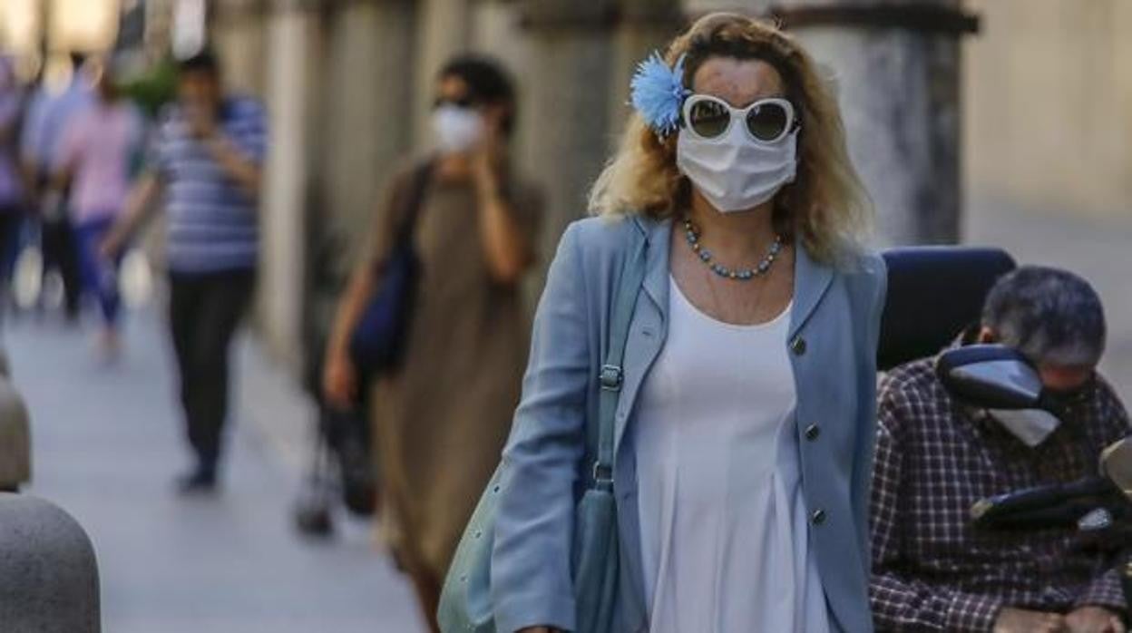 Una mujer camina por una calle de Sevilla con la mascarilla puesta