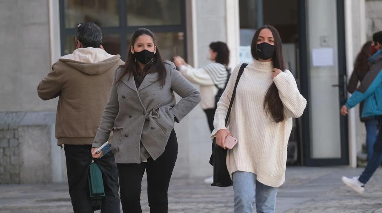 Una jóvenes con mascarilla caminan por la calle de Cádiz