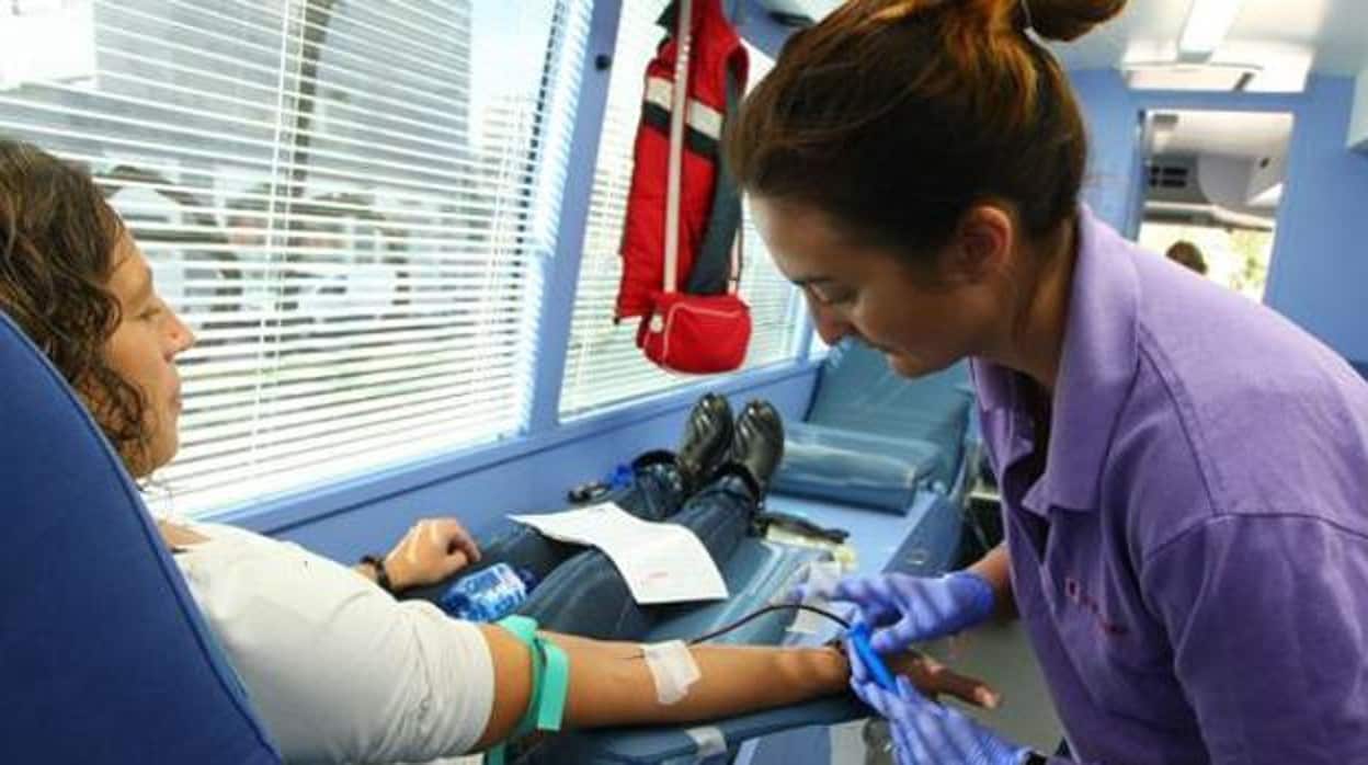 Una mujer dona sangre en una unidad móvil