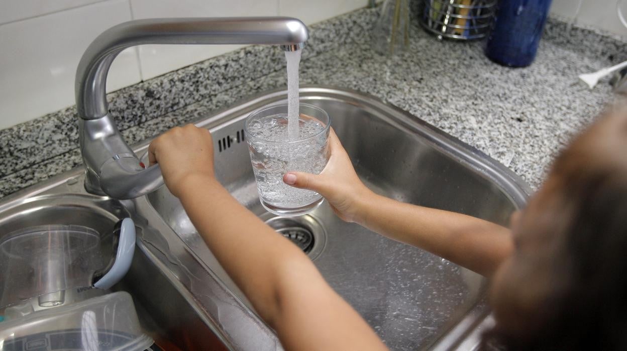 Una niña abriendo el grifo del agua en su casa