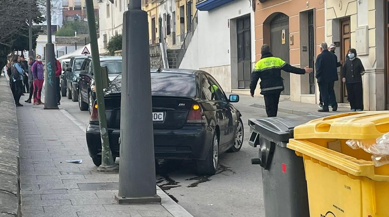 Un agente despejal a presencia de vecinos delante del coche siniestrado en un semáforo de la calle Obispo Pérez Muñoz