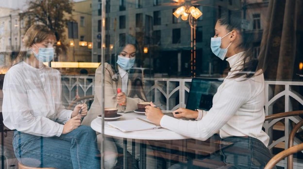 Tres mujeres en el interior de una cafetería con la mascarilla puesta