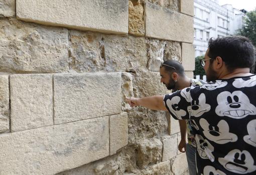 Unos jóvenes señalan las caras aparecidas en el monumento en 2019