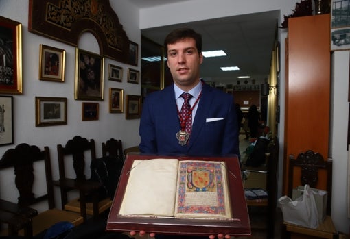 El hermano mayor de la Caridad, Carlos Pérez, muestra el libro de reglas