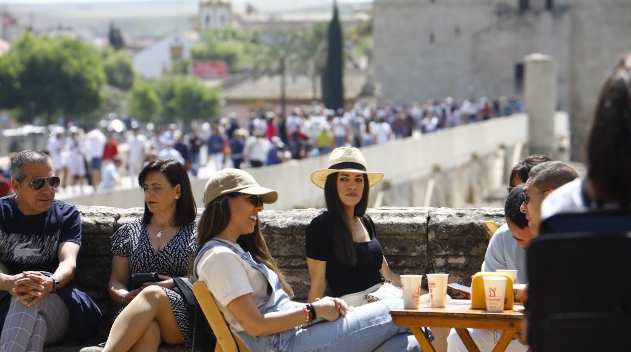 Clientes de un bar, en un velador junto al Puente Romano