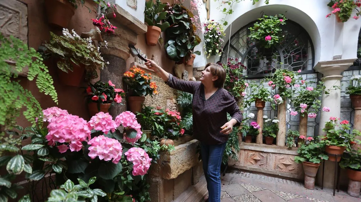 Una mujer acicala su patio antes de abrir las puertas de su casa a los visitantes