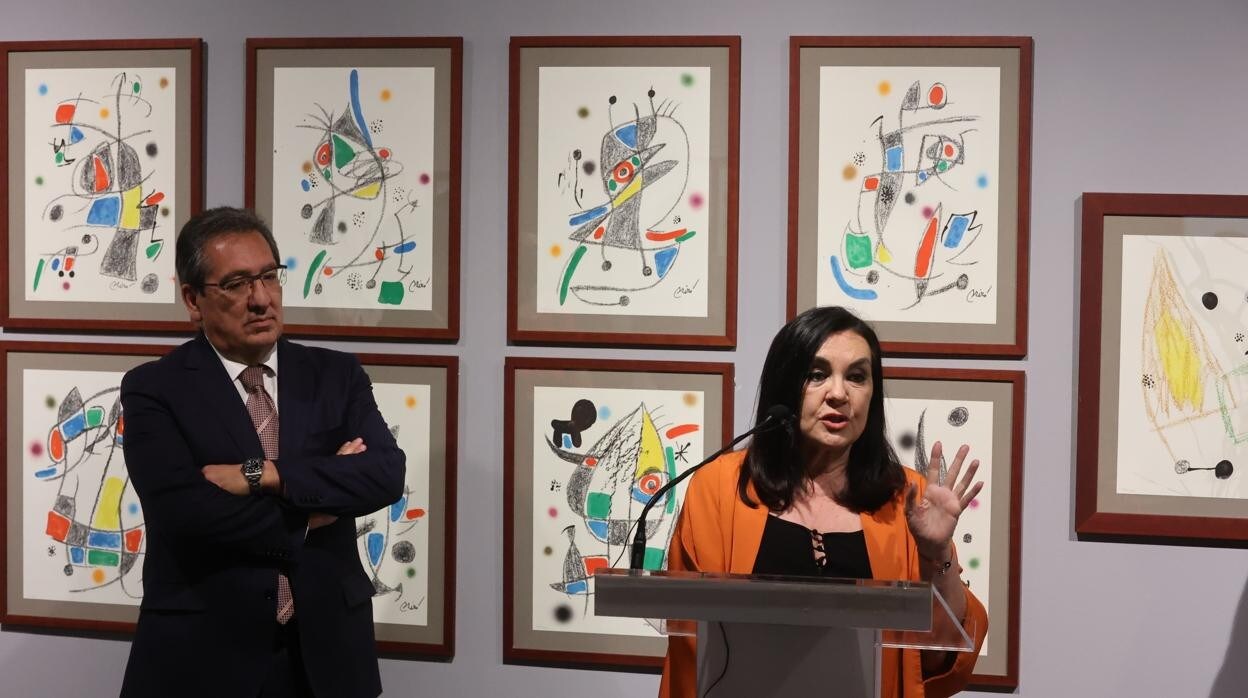 Antonio Pulido atiende las explicaciones de la comisaria Marisa Oropesa; de fondo, algunas de las litografías de Miró