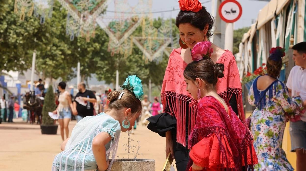 Dos niñas beben agua en una fuente de la Feria de Córdoba