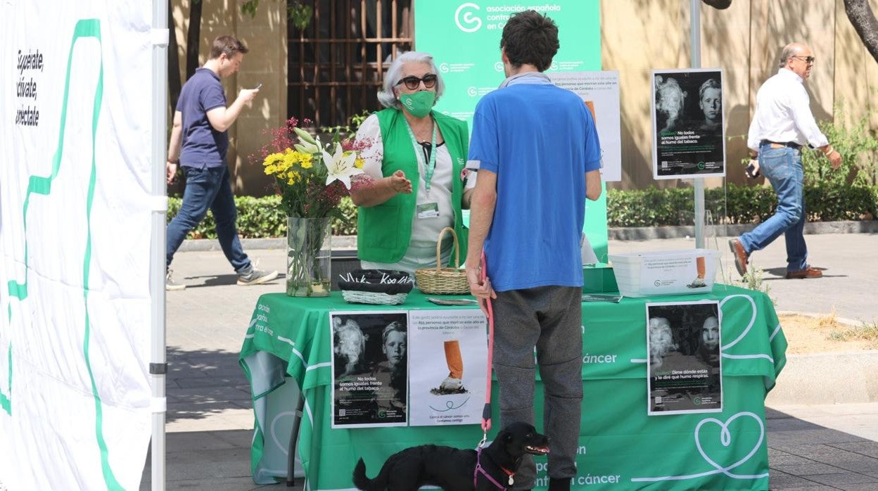 Una voluntaria de la AECC informa a un ciuddano de los perjuicios del tabaco