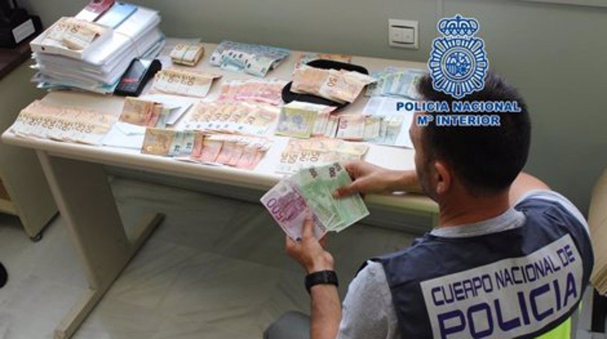 Un policía nacional cuenta el dinero intervenido a esta red en un registro