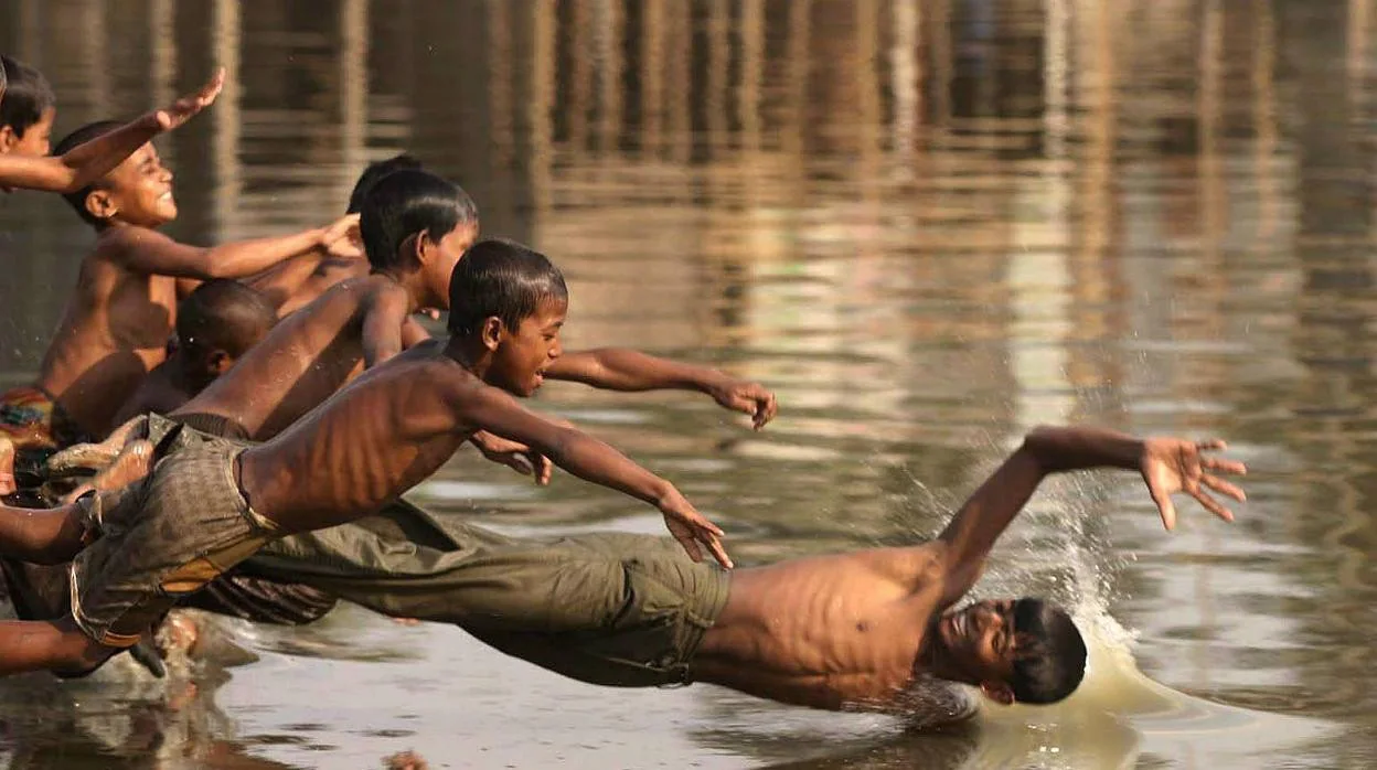 Niños en un río bañándose.