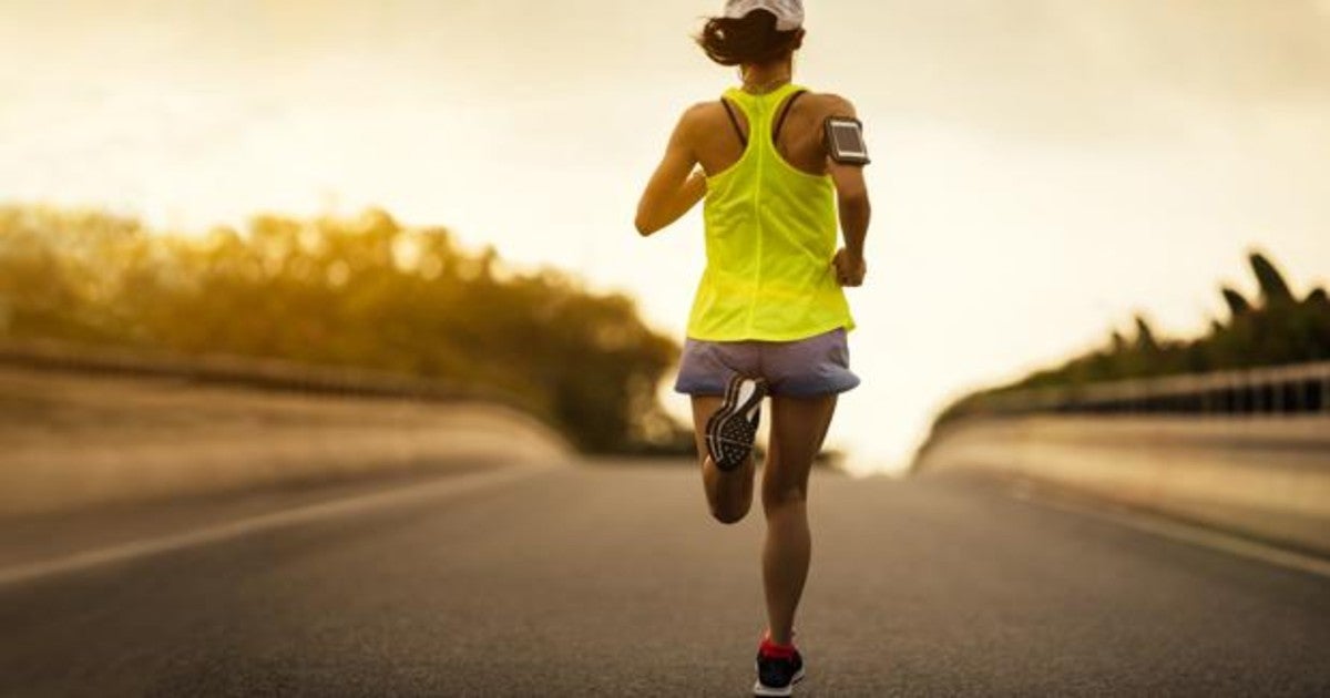 Atleta masculino árabe muscular que usa auriculares inalámbricos corriendo  en la cinta de correr en el gimnasio