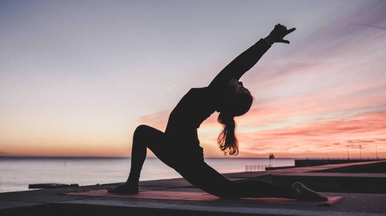 Una mujer practicando yoga sobre una esterilla.