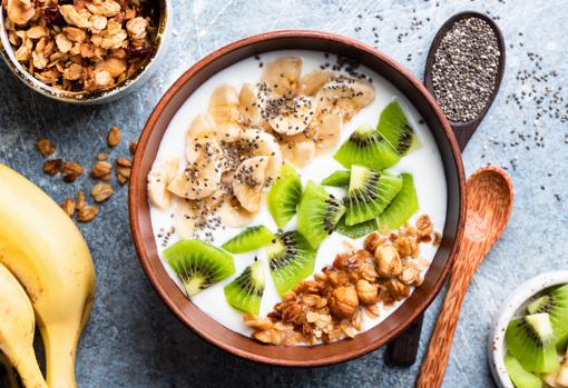 Bowl de yogur griego con nueces, avellanas, plátano, kiwi y semillas de chía.