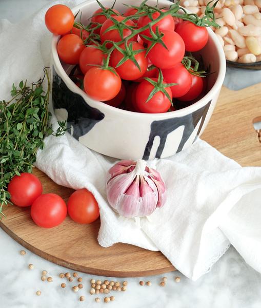 Tomatitos cherry, cabeza de ajos, alubias cocidas y el resto de ingredientes necesarios para preparar la receta.