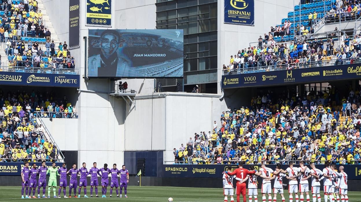 Los equipos, antes de empezar el partido guardando un minuto de silencio con la imagen de Manzorro al fondo.