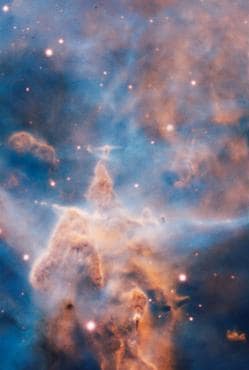«La Montaña Mística», un pilar de gas y polvo de tres años luz de alto devorado por la brillante luz de estrellas cercanas