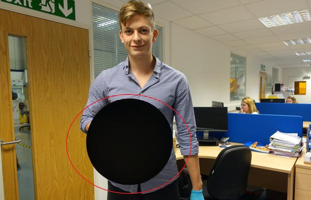 Un investigador sostiene un objeto circular rociado con «Vantablack»