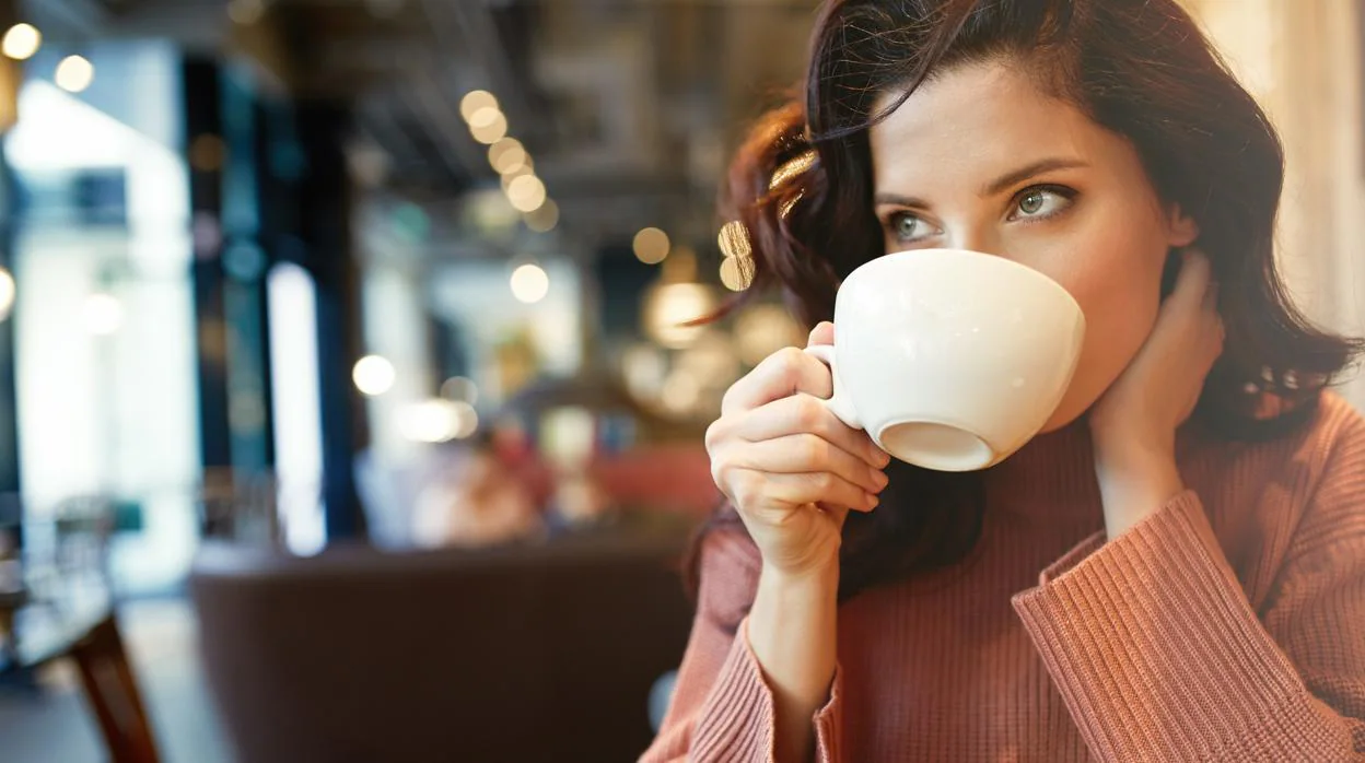 Una joven bebe una taza de café