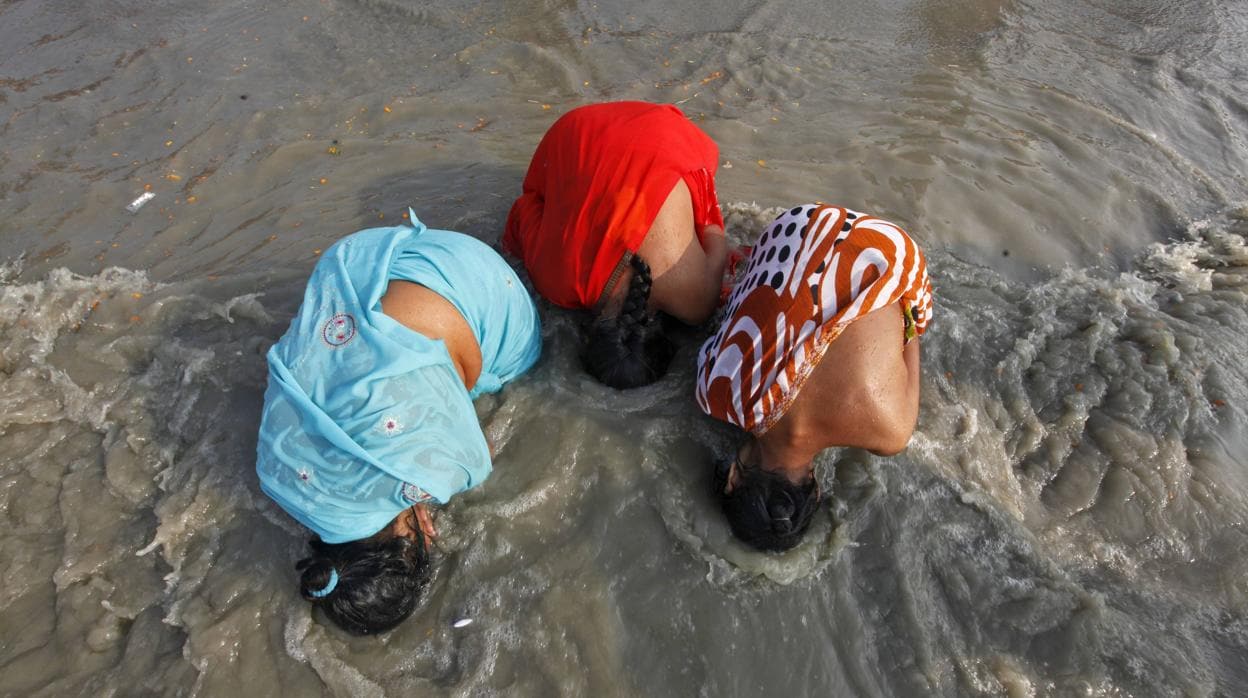 Tres peregrinas hindúes se bañan en las contaminadas aguas del río Ganges