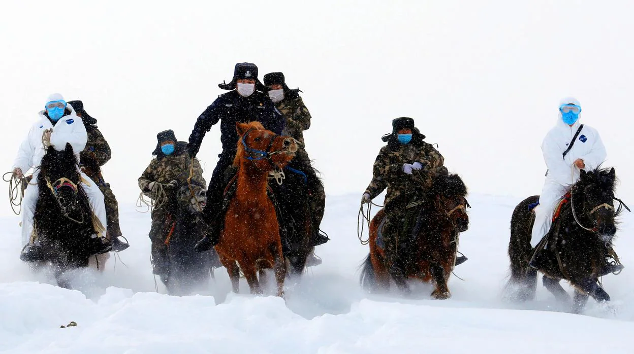 Autoridades fronterizas cabalgan a través de la nieve para informar a los residentes sobre la epidemia de coronavirus en una región montañosa de Altay, en Xinjiang, China, el pasado 19 de febrero